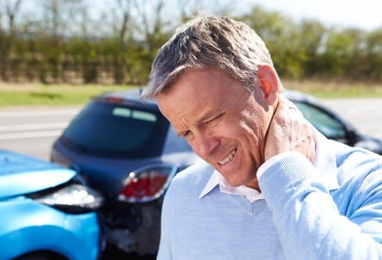 A man holding his hand to his ear while standing in front of an accident.